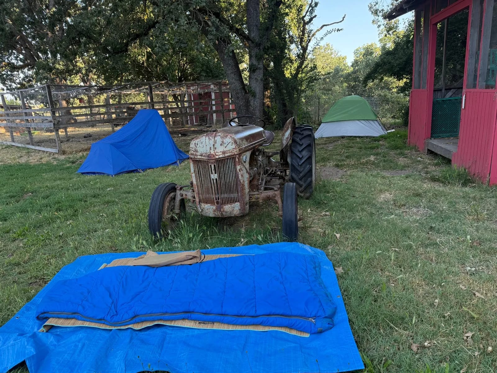 Tents pitched near an antique tractor for overnight guests