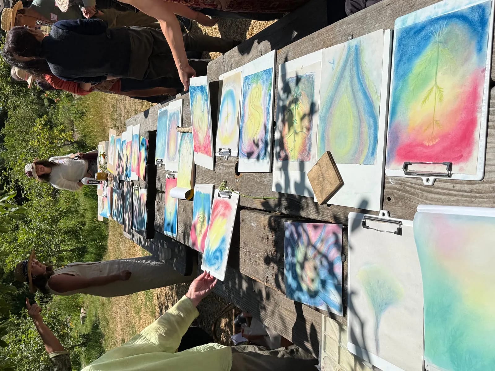 Rows of finished pastel drawings laid out on an outdoor table