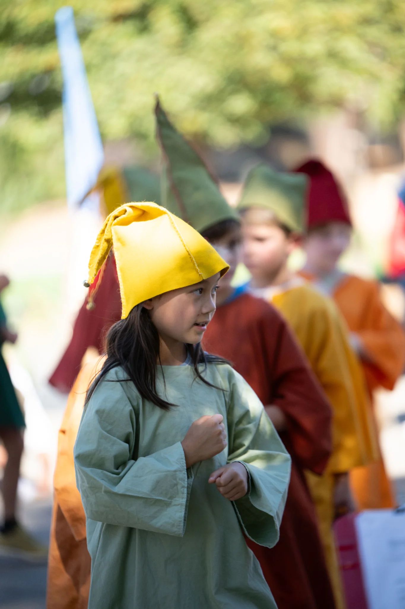 Young elementary student in yellow felt hat and faded green tunic