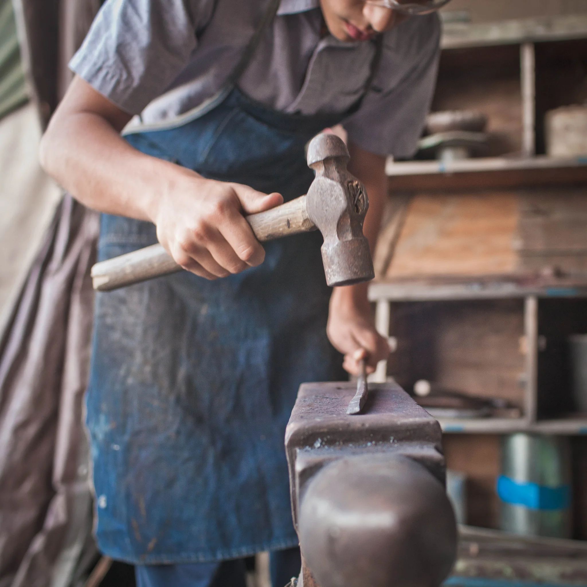 High School student hammering metal on an anvil