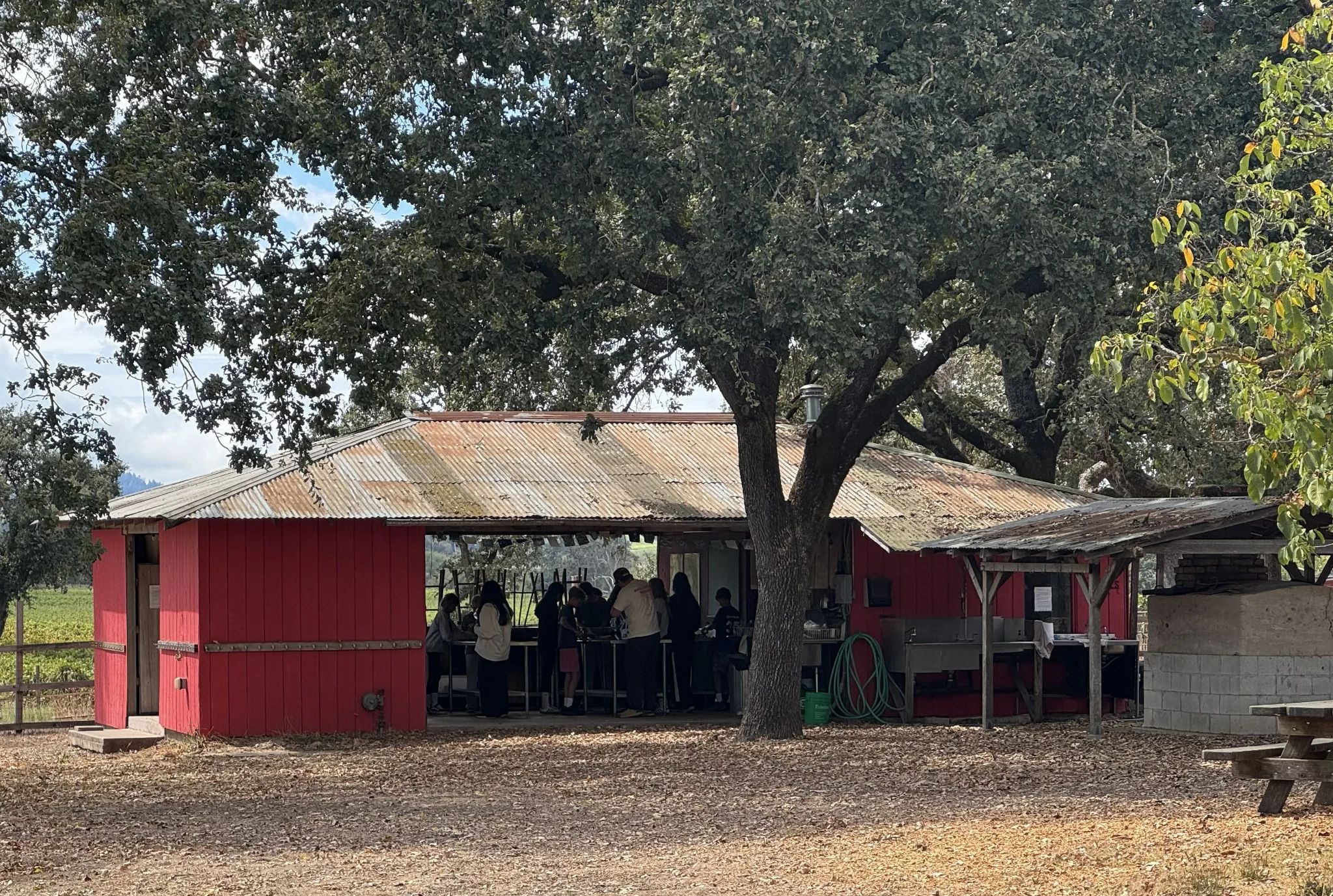 Red farm building outdoor kitchen with people inside