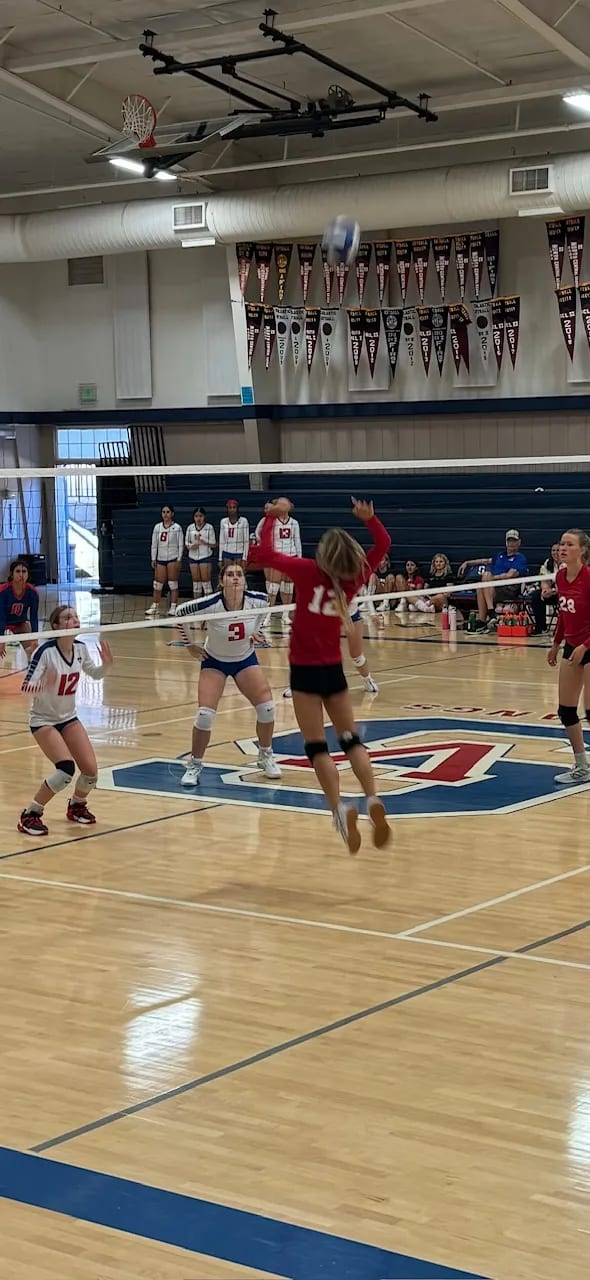 A Mustangs hitter goes up at the net during a league volleyball match.