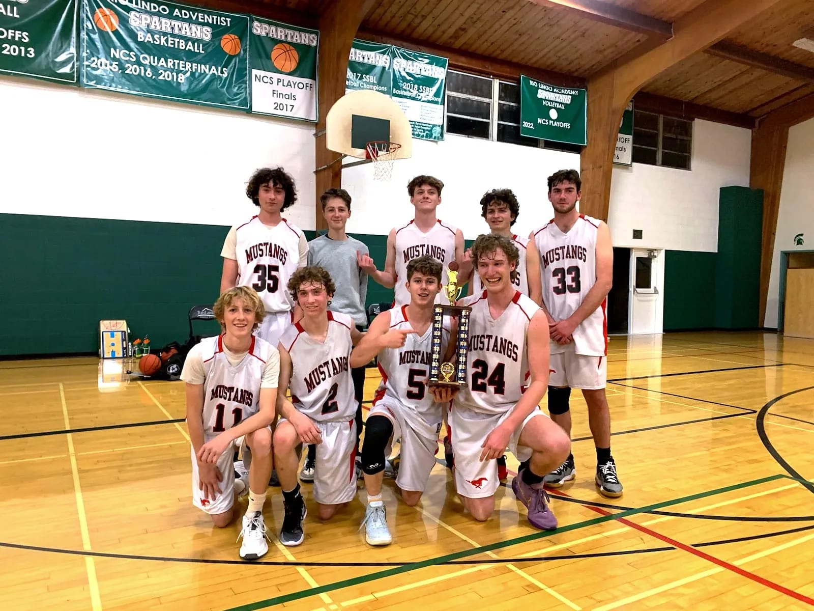 The boys' basketball team gathers around its championship trophy.