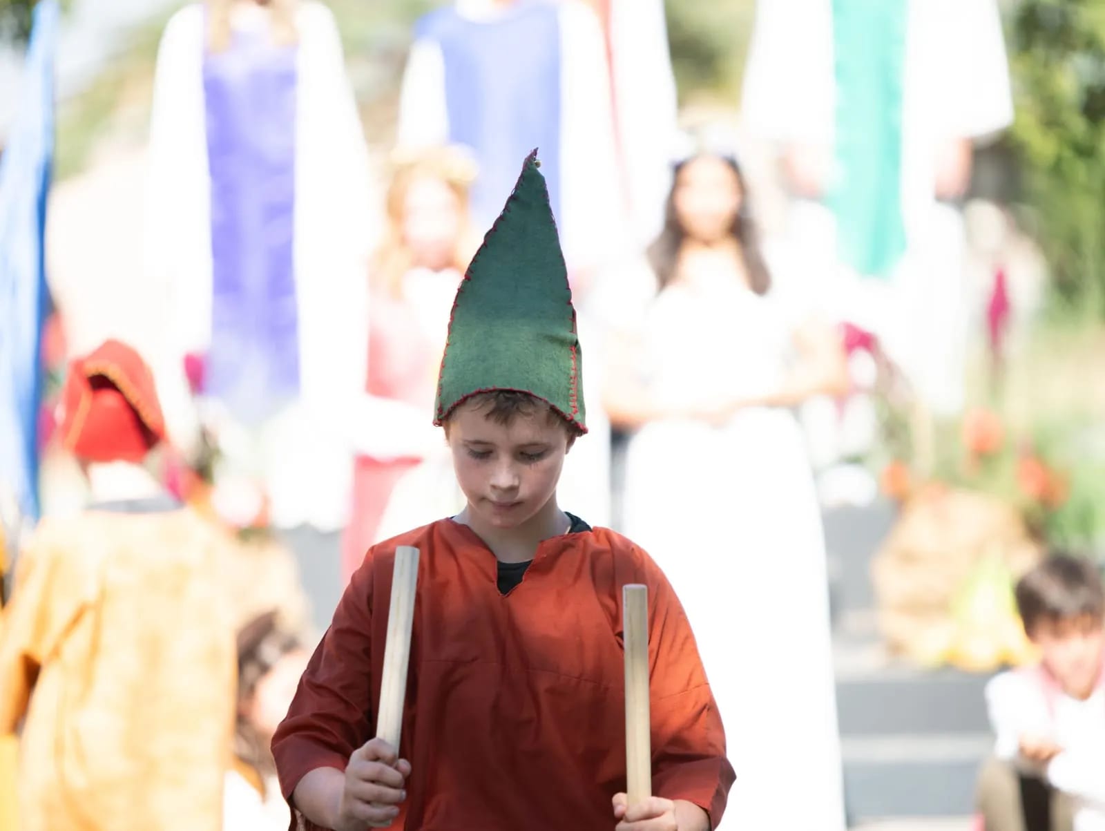 A child carries staves in the Michaelmas procession, banners following behind.