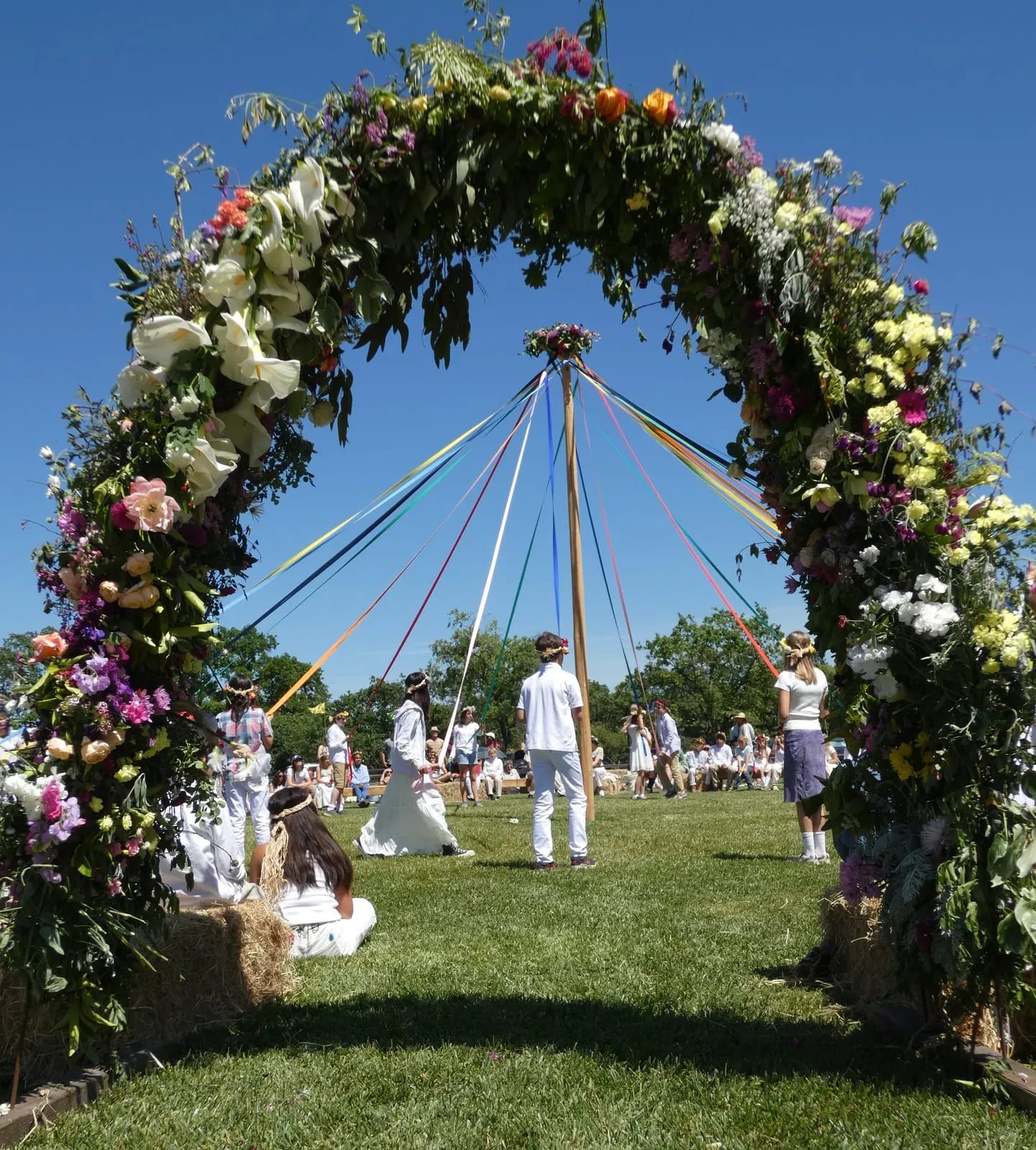 The maypole and its ribbons, seen through the May Faire flower arch.