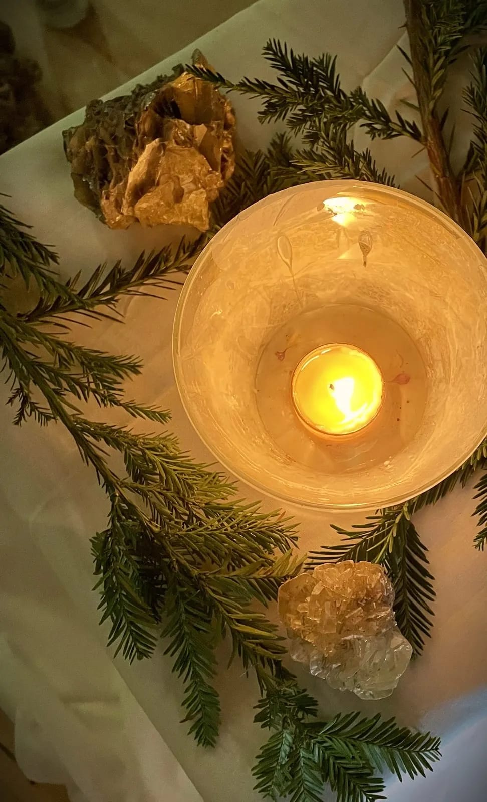 A candle and quartz among fir boughs at the Festival of Lights.
