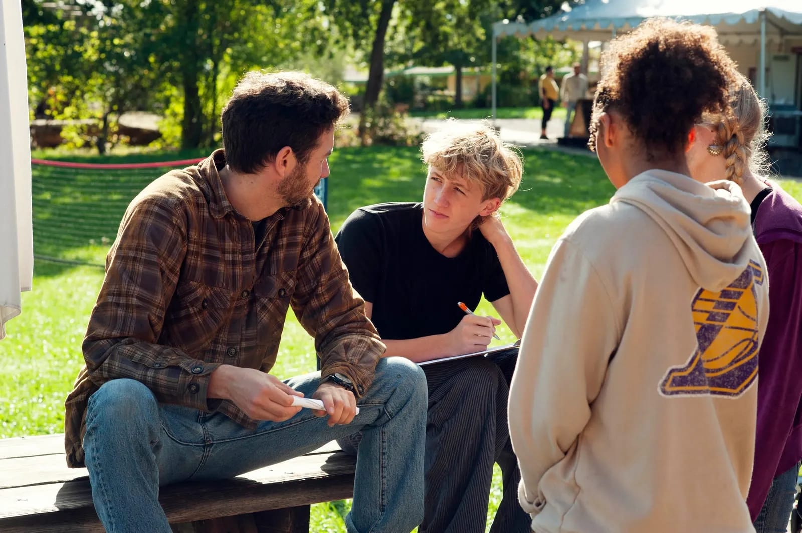 A teacher and students talking over notes at a picnic table.